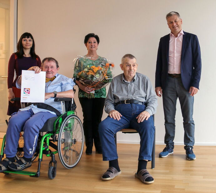 personen im rollstuhl und personen stehen dahinter